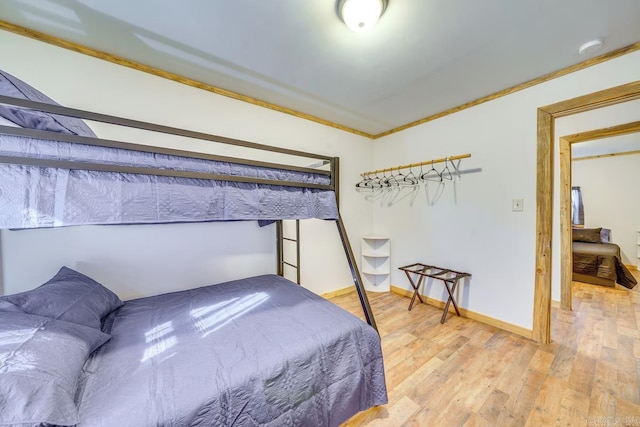 bedroom with baseboards, ornamental molding, and light wood finished floors