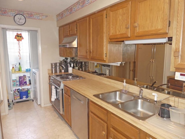 kitchen with under cabinet range hood, appliances with stainless steel finishes, light countertops, and a sink