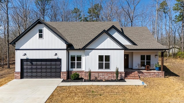 modern farmhouse featuring covered porch, concrete driveway, a front yard, and a shingled roof