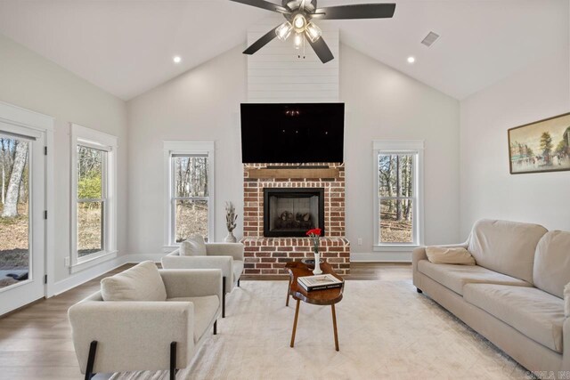 living area with visible vents, high vaulted ceiling, ceiling fan, and light wood finished floors