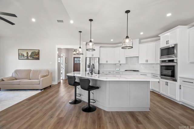 kitchen featuring visible vents, backsplash, dark wood-style floors, open floor plan, and stainless steel appliances