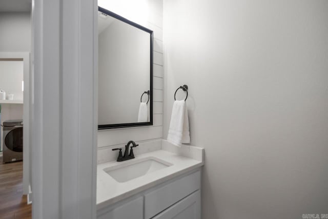 bathroom with washer / dryer, wood finished floors, and vanity