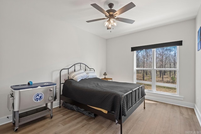 bedroom featuring baseboards, a ceiling fan, and light wood finished floors