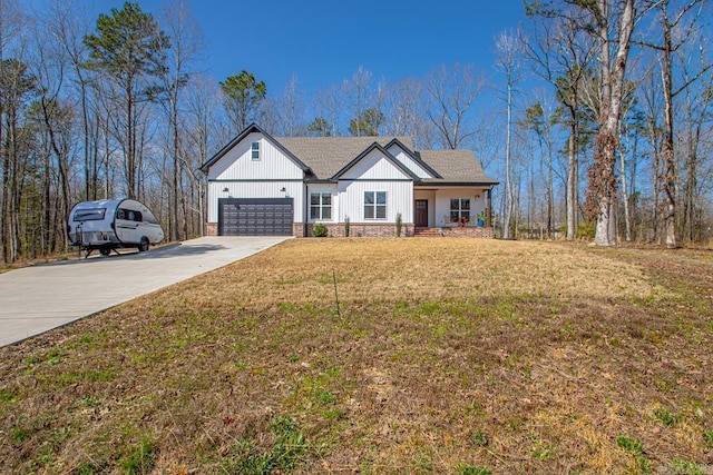 modern inspired farmhouse featuring a front lawn, a garage, and driveway