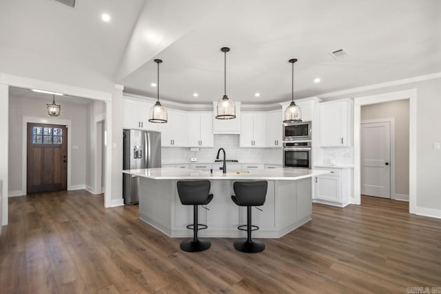 kitchen featuring visible vents, a sink, stainless steel appliances, white cabinets, and backsplash