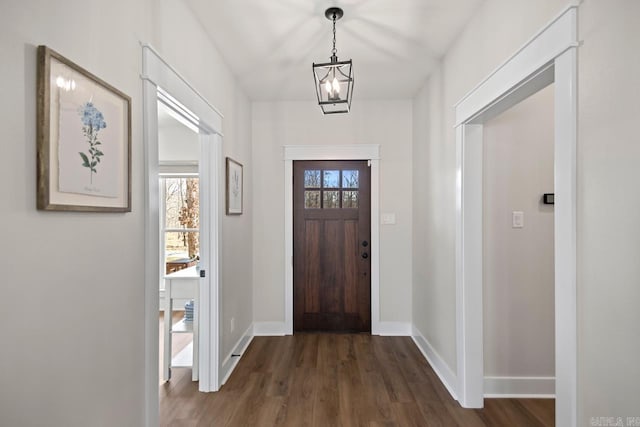 foyer entrance with an inviting chandelier, a healthy amount of sunlight, dark wood-style flooring, and baseboards