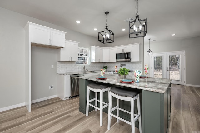 kitchen with visible vents, a sink, white cabinets, appliances with stainless steel finishes, and a chandelier