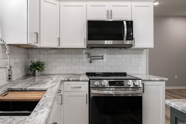 kitchen with white cabinetry, decorative backsplash, light stone counters, and appliances with stainless steel finishes