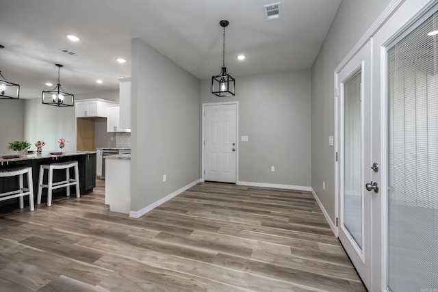 foyer entrance featuring light wood-style flooring, baseboards, and visible vents