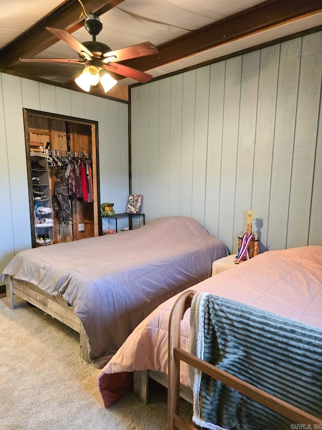 carpeted bedroom featuring beamed ceiling, a closet, and ceiling fan