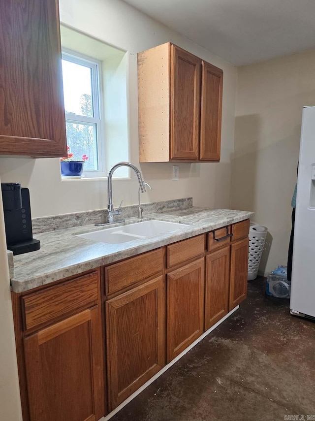 kitchen featuring white refrigerator with ice dispenser, brown cabinetry, and a sink