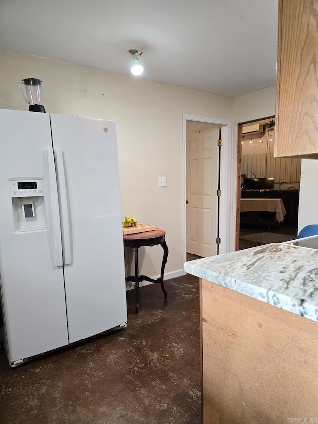 kitchen with baseboards, white fridge with ice dispenser, concrete floors, and light countertops