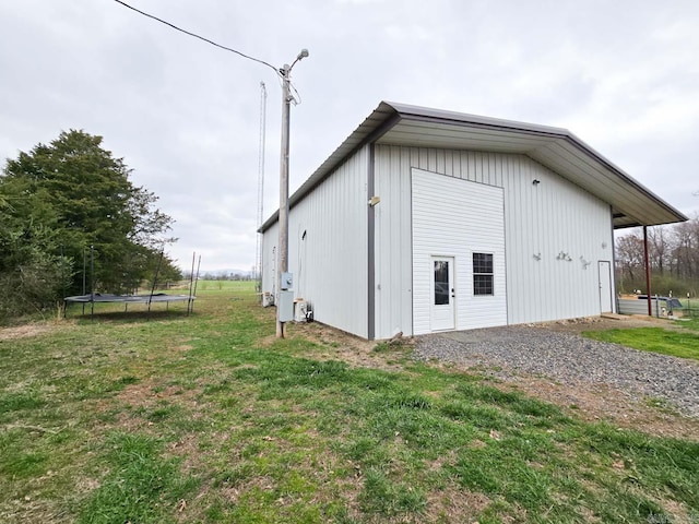 view of outdoor structure featuring a trampoline, gravel driveway, and an outdoor structure