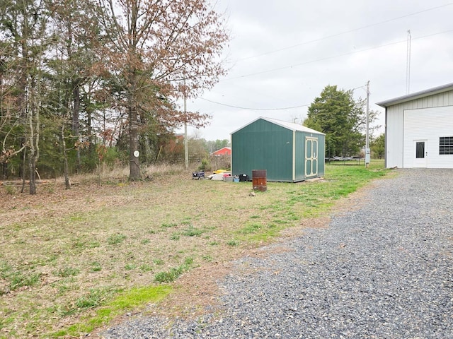 view of yard with an outbuilding, a shed, and gravel driveway