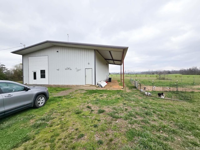 view of pole building with a lawn and fence