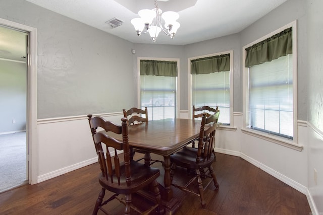 dining space featuring dark wood-style floors, baseboards, visible vents, and a chandelier