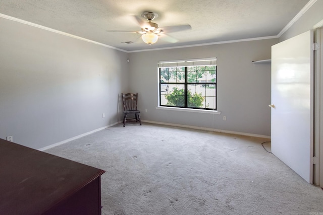 spare room with a textured ceiling, carpet flooring, a ceiling fan, and ornamental molding