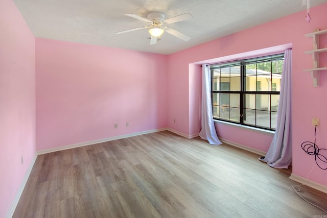 empty room with baseboards, wood finished floors, and a ceiling fan