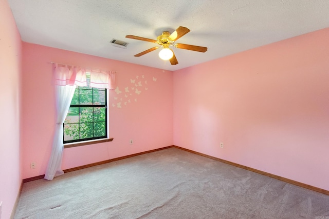 carpeted spare room featuring visible vents, baseboards, a textured ceiling, and ceiling fan