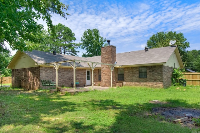 rear view of property with a yard, brick siding, a chimney, and fence