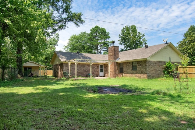 rear view of property featuring a yard, a chimney, and fence