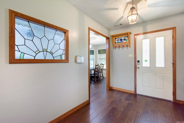 foyer entrance featuring visible vents, dark wood-style flooring, and baseboards