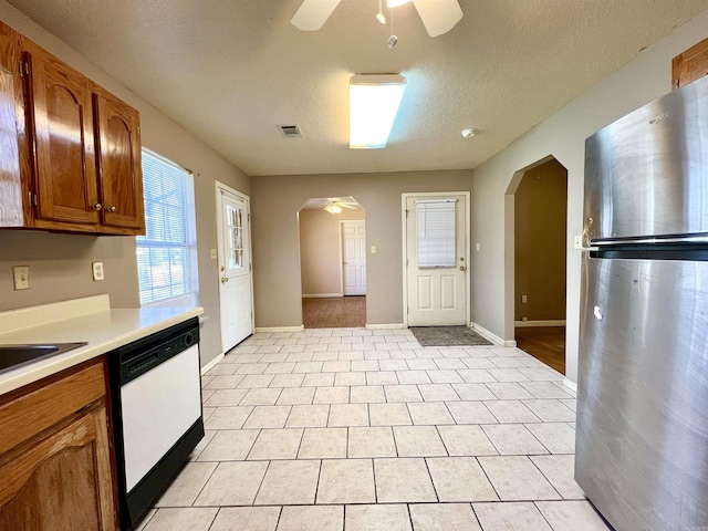 kitchen featuring arched walkways, ceiling fan, white dishwasher, and freestanding refrigerator