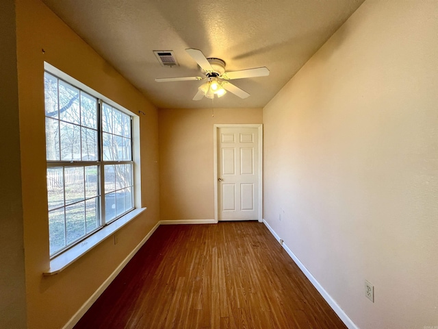 spare room featuring visible vents, a ceiling fan, a textured ceiling, dark wood finished floors, and baseboards