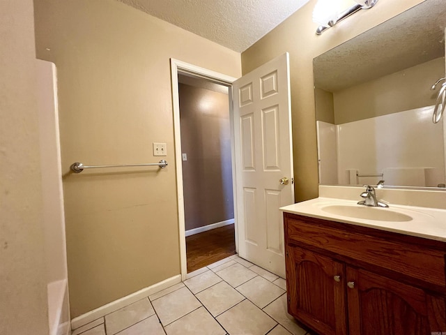 bathroom with tile patterned floors, a textured ceiling, vanity, and baseboards