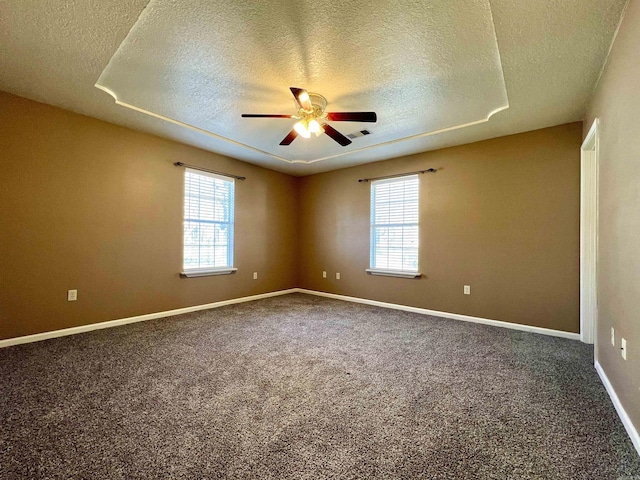 carpeted spare room featuring a wealth of natural light, visible vents, baseboards, and a ceiling fan