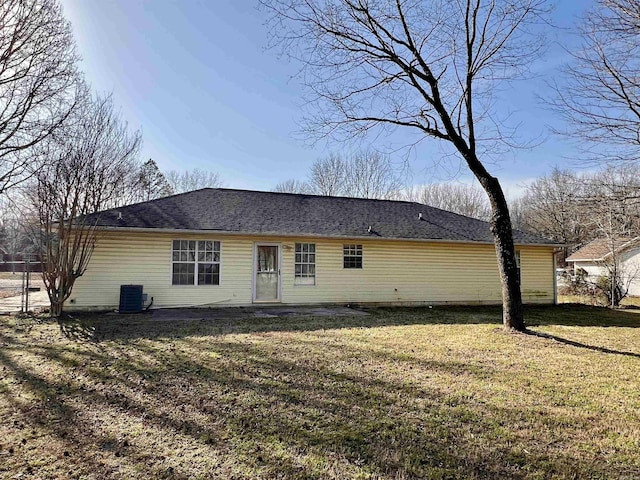 rear view of property with central air condition unit and a lawn