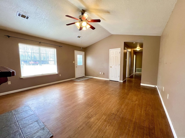 unfurnished room with visible vents, lofted ceiling, a ceiling fan, and hardwood / wood-style flooring