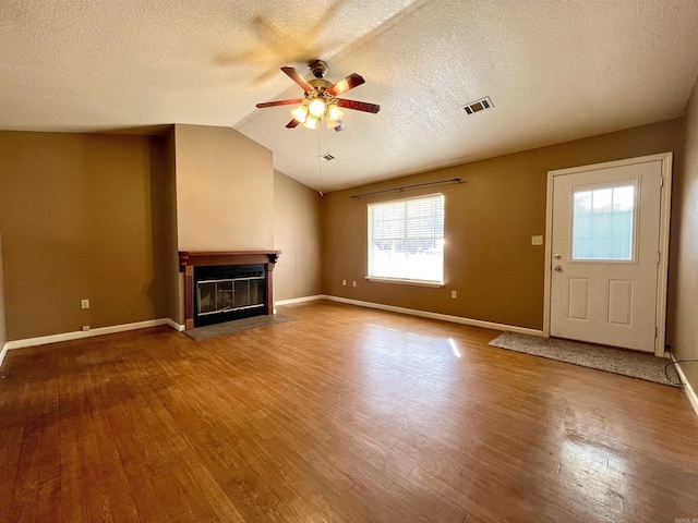 unfurnished living room featuring visible vents, lofted ceiling, ceiling fan, hardwood / wood-style flooring, and a glass covered fireplace