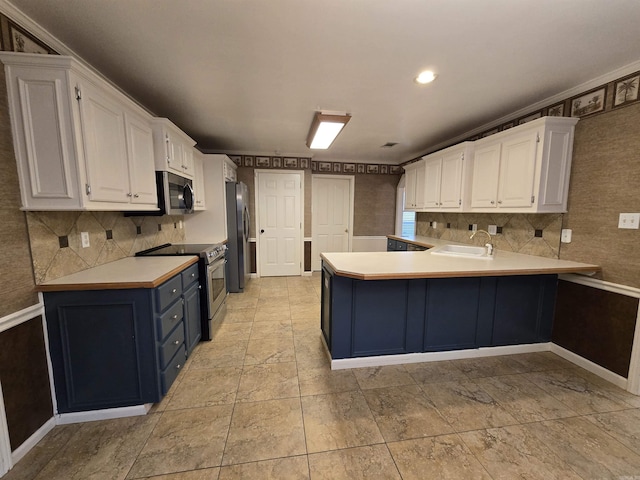 kitchen with a peninsula, a sink, light countertops, appliances with stainless steel finishes, and white cabinetry