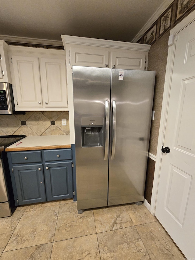 kitchen with ornamental molding, light countertops, white cabinets, appliances with stainless steel finishes, and blue cabinets