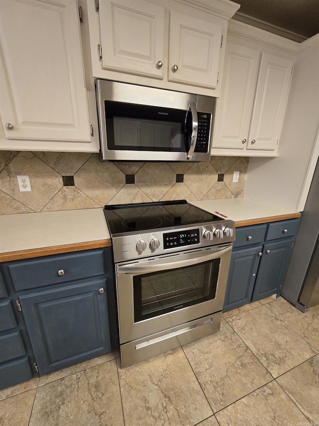 kitchen featuring stainless steel appliances, light countertops, white cabinetry, blue cabinets, and backsplash