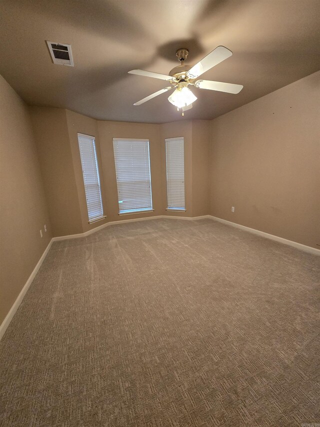 carpeted spare room with a ceiling fan, baseboards, and visible vents