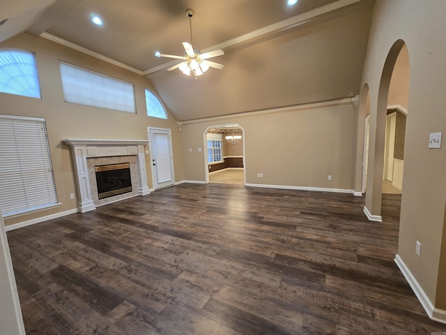 unfurnished living room with dark wood finished floors, arched walkways, ceiling fan, and a tiled fireplace