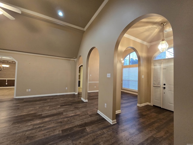 foyer with ornamental molding, ceiling fan with notable chandelier, baseboards, a towering ceiling, and dark wood-style flooring