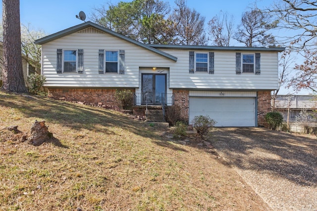 split foyer home featuring brick siding, a garage, and driveway