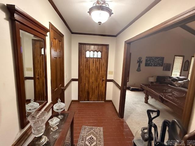 foyer entrance with baseboards, brick floor, and ornamental molding