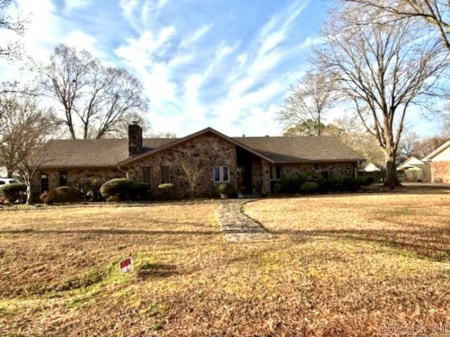 view of front of property with stone siding, a chimney, and a front lawn
