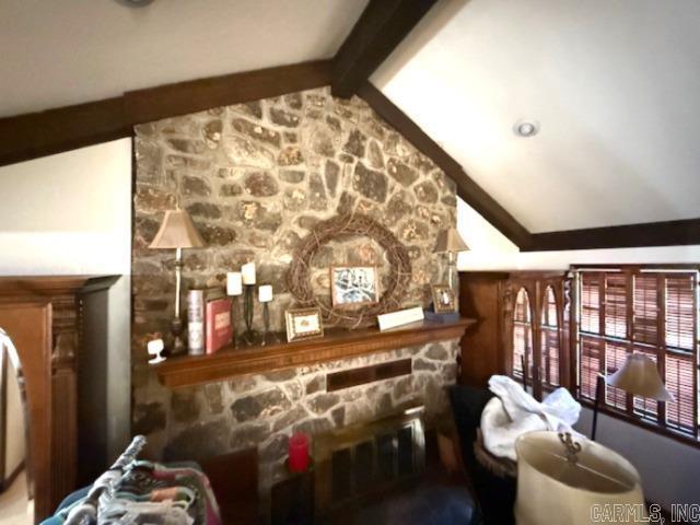 interior space with a stone fireplace and lofted ceiling with beams