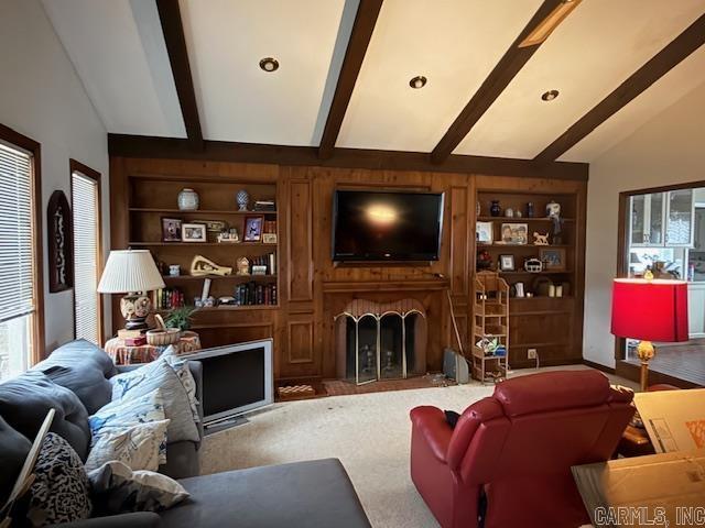 living room featuring lofted ceiling with beams, carpet flooring, built in shelves, and a fireplace with flush hearth