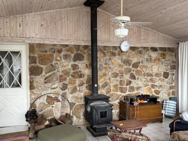 interior details featuring wood ceiling, a wood stove, and ceiling fan