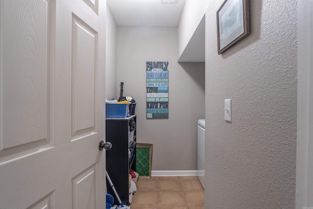 washroom with light tile patterned floors, baseboards, and a textured wall