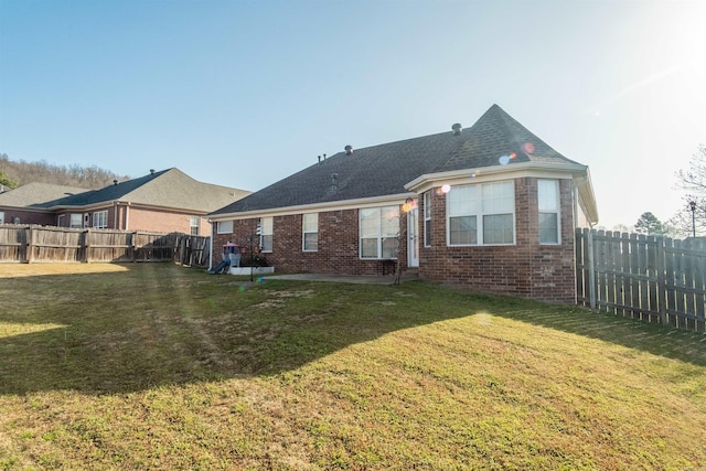 back of property featuring brick siding, a fenced backyard, and a lawn