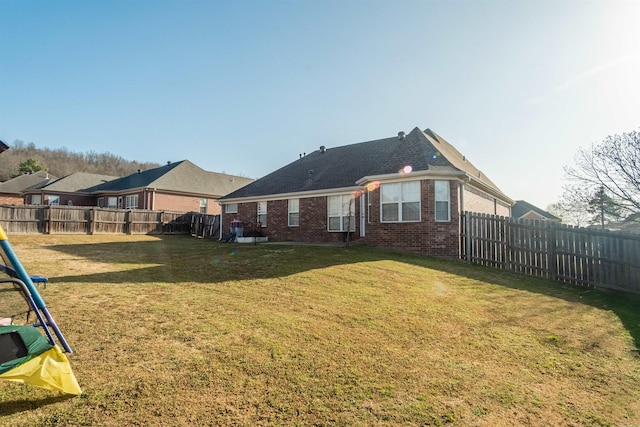 back of house with a lawn, brick siding, and a fenced backyard