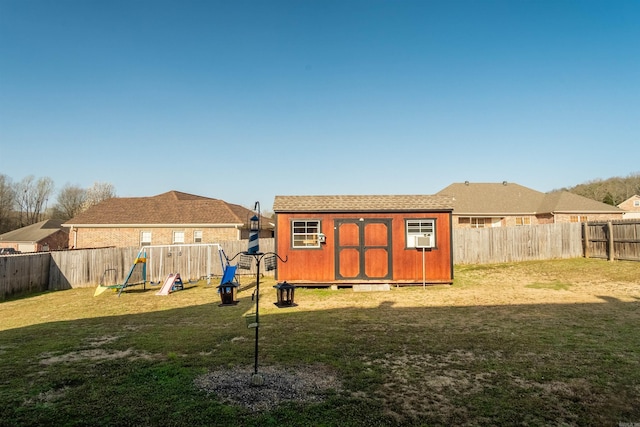 view of yard featuring an outbuilding, a fenced backyard, a storage shed, and a playground