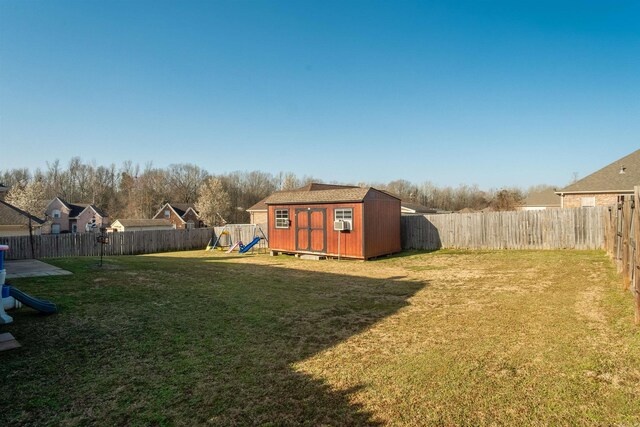 view of yard with a fenced backyard, a storage shed, an outdoor structure, and a playground